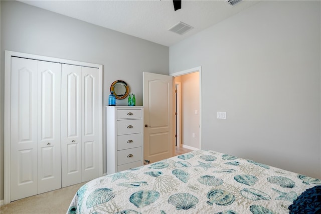 bedroom with a textured ceiling, light carpet, ceiling fan, and a closet