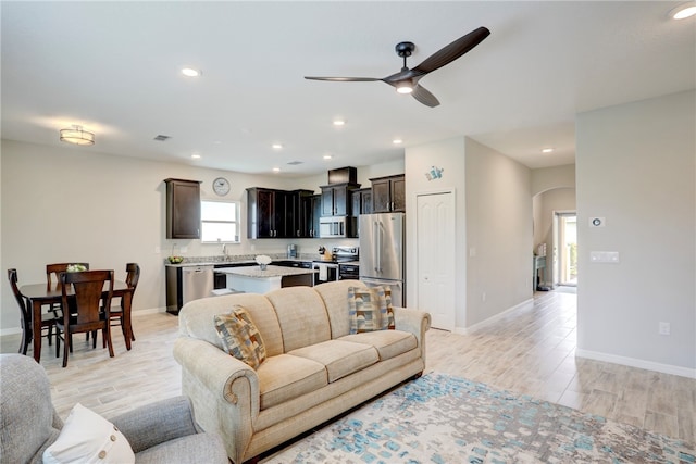 living room with ceiling fan, sink, and light hardwood / wood-style flooring