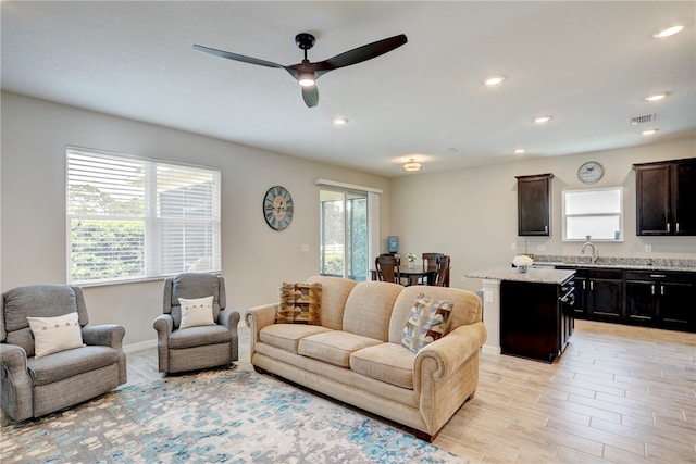 living room featuring ceiling fan, sink, and light hardwood / wood-style flooring