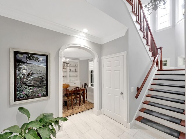 stairway with built in shelves, a chandelier, and crown molding