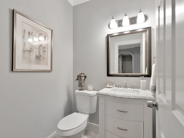 bathroom with toilet, vanity, and crown molding