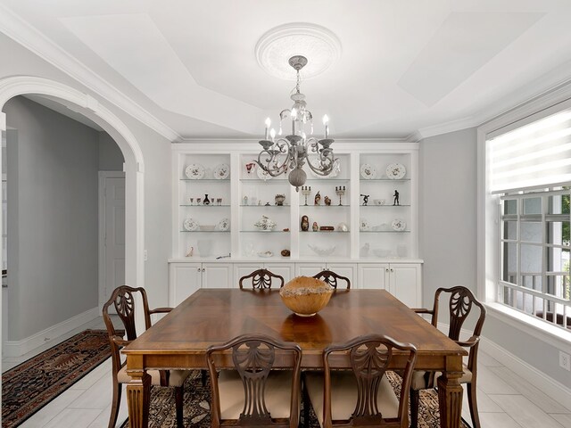 dining space featuring built in features, a chandelier, and crown molding