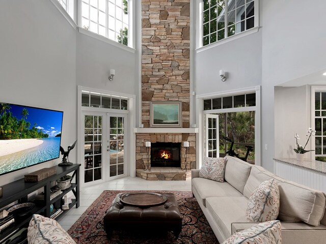 living room featuring a stone fireplace, a towering ceiling, and a healthy amount of sunlight