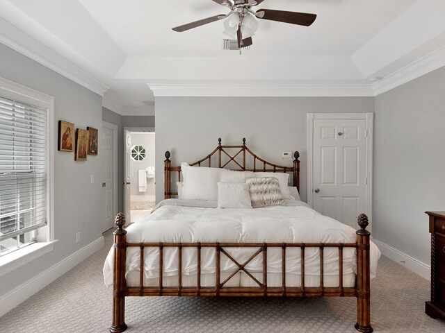 carpeted bedroom featuring ensuite bathroom, a raised ceiling, ceiling fan, and crown molding