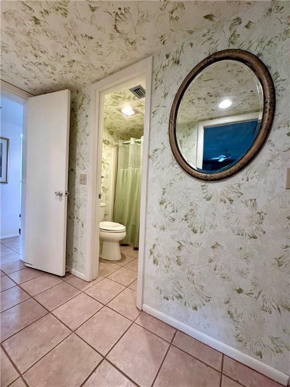 bathroom featuring baseboards, tile patterned floors, and wallpapered walls