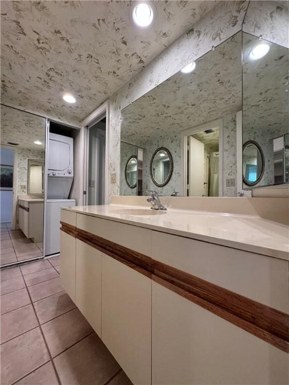 full bath featuring wallpapered walls, tile patterned flooring, stacked washer / drying machine, and vanity