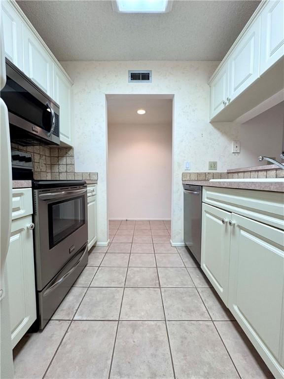 kitchen featuring stainless steel appliances, light countertops, visible vents, and white cabinets