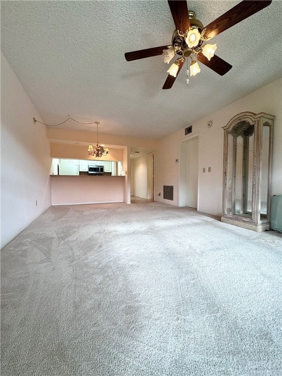 unfurnished living room featuring carpet, visible vents, a textured ceiling, and ceiling fan with notable chandelier