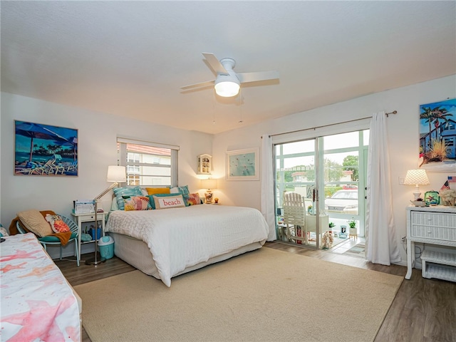 bedroom featuring multiple windows, dark hardwood / wood-style flooring, access to outside, and ceiling fan