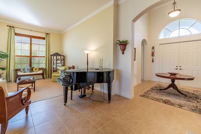 foyer with light tile patterned floors, ornamental molding, and a towering ceiling