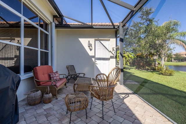 view of patio with glass enclosure, grilling area, a water view, and an outdoor hangout area