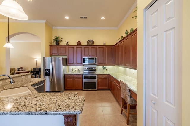 kitchen featuring sink, light stone counters, appliances with stainless steel finishes, ornamental molding, and pendant lighting