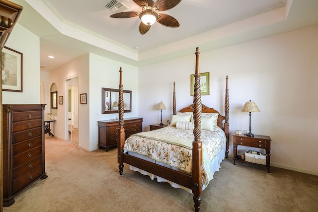 carpeted bedroom featuring ornamental molding, ceiling fan, ensuite bath, and a tray ceiling