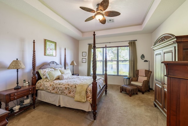 carpeted bedroom with ceiling fan and a tray ceiling