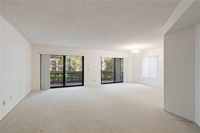 carpeted spare room featuring a textured ceiling and a chandelier