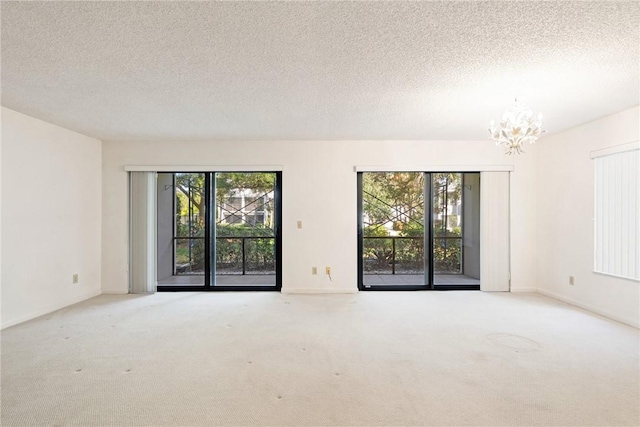 carpeted spare room featuring a textured ceiling and a chandelier