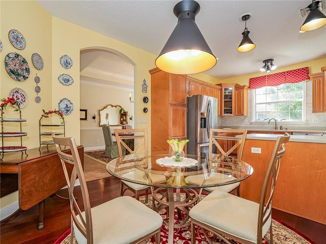 dining area featuring crown molding, baseboards, wood finished floors, and arched walkways