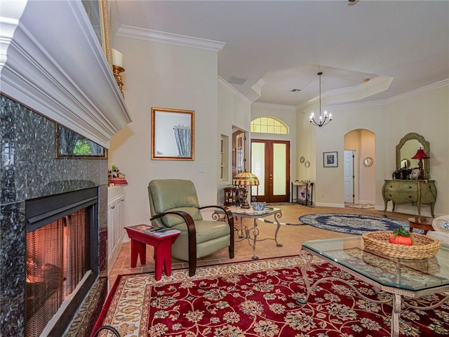 living room with crown molding, baseboards, arched walkways, a notable chandelier, and a fireplace