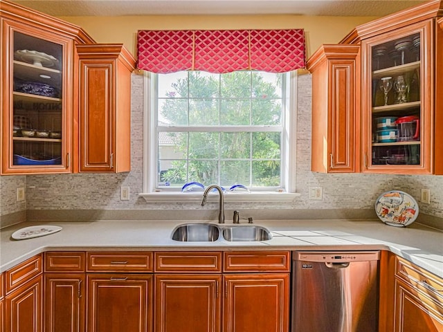 kitchen with a sink, light countertops, glass insert cabinets, and dishwasher