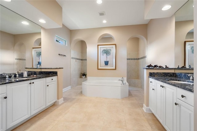 bathroom featuring a sink, two vanities, a bath, and recessed lighting