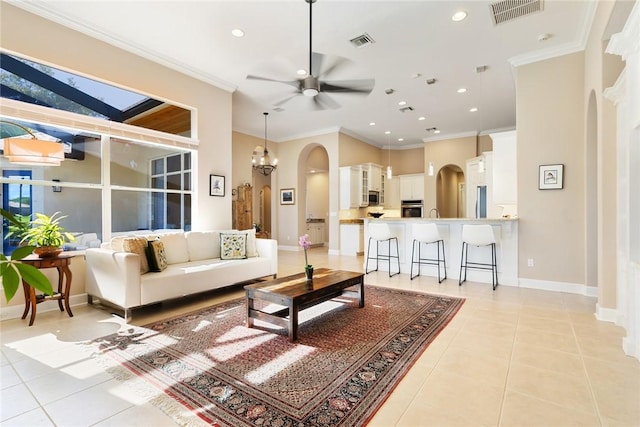 living room with visible vents, arched walkways, light tile patterned flooring, and crown molding