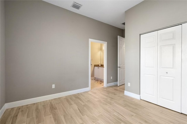 unfurnished bedroom with light wood-style floors, visible vents, a closet, and baseboards