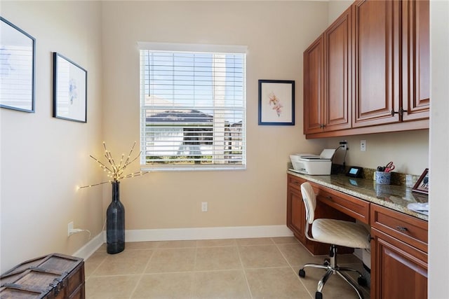 office area with light tile patterned flooring, baseboards, and built in desk