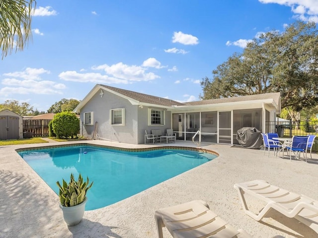 view of swimming pool with a patio, a storage shed, and a sunroom