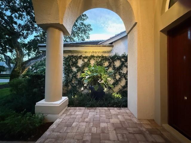 exterior space featuring ornate columns, stucco siding, and elevator
