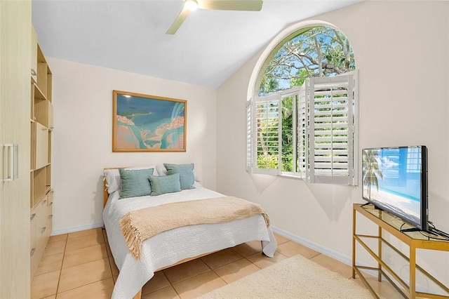 tiled bedroom with baseboards, multiple windows, and lofted ceiling