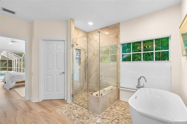 bathroom featuring a freestanding bath, a shower stall, wood finished floors, and visible vents