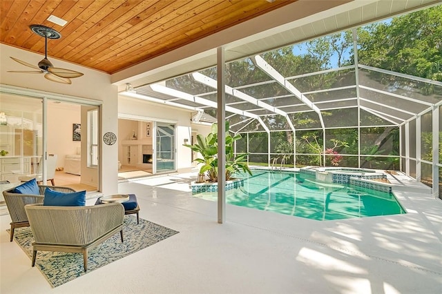 view of swimming pool with a ceiling fan, glass enclosure, a pool with connected hot tub, and a patio area