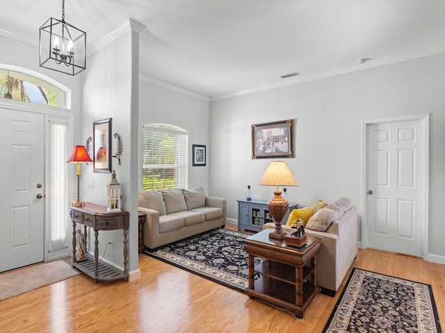 living room with a notable chandelier, plenty of natural light, and ornamental molding