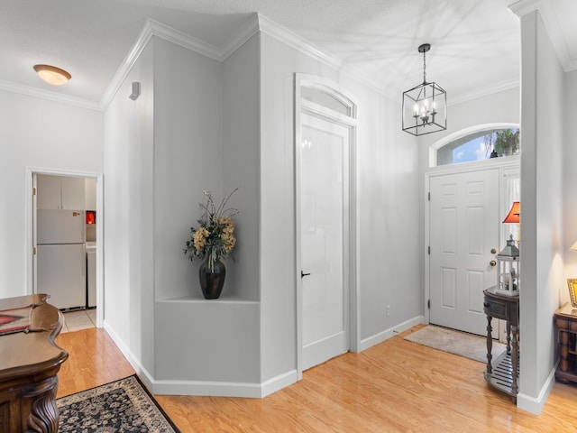 foyer featuring light hardwood / wood-style flooring, a notable chandelier, and ornamental molding