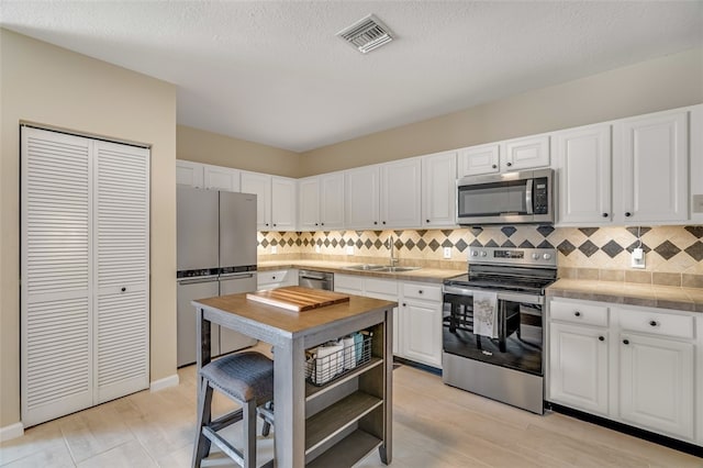 kitchen featuring white cabinetry, appliances with stainless steel finishes, sink, and backsplash