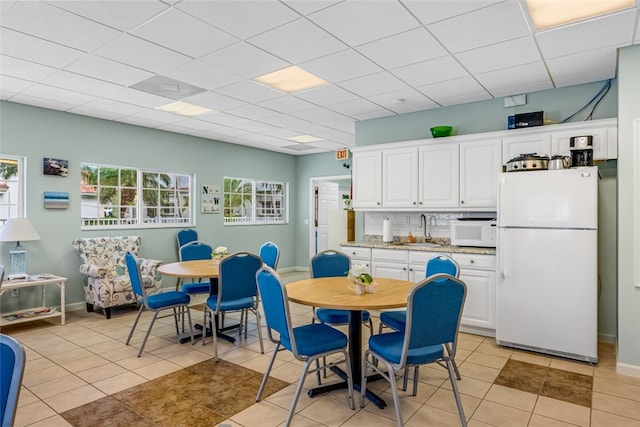 kitchen featuring white appliances, sink, light tile patterned floors, and white cabinets