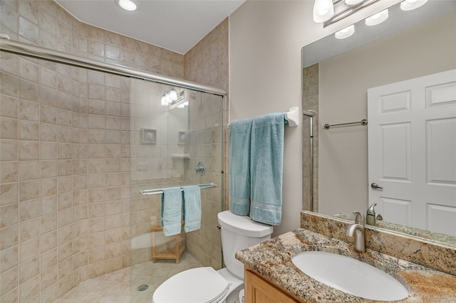 bathroom featuring toilet, vanity, and a shower with shower door