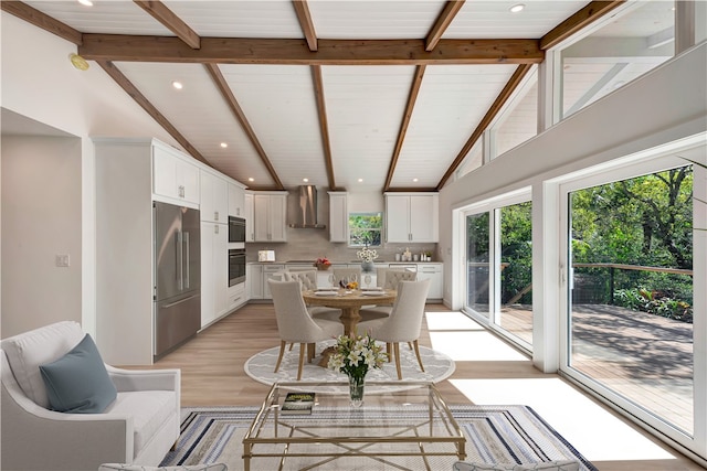 dining area featuring light wood-type flooring and lofted ceiling with beams