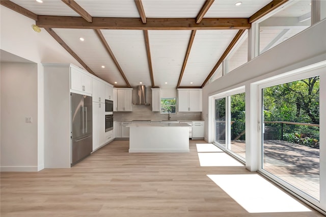 kitchen featuring backsplash, high end fridge, wall chimney exhaust hood, white cabinetry, and black oven