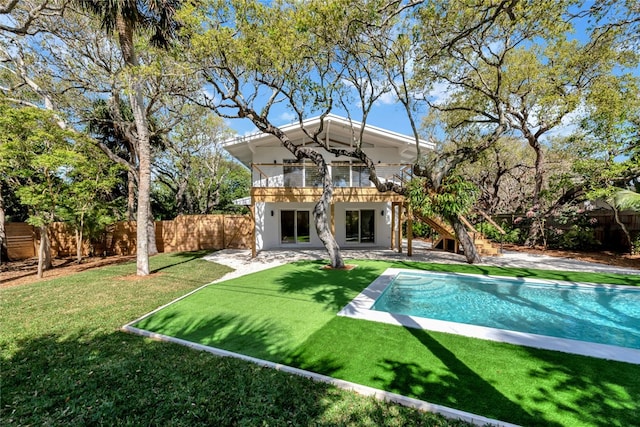 back of property with a fenced in pool, a balcony, a lawn, and a patio