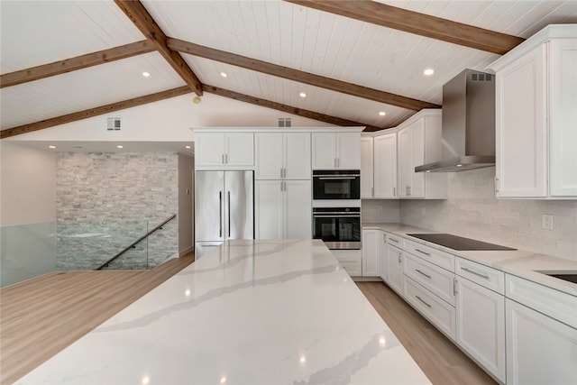 kitchen with wall chimney exhaust hood, white cabinetry, light stone countertops, and appliances with stainless steel finishes