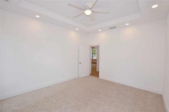 carpeted empty room featuring ceiling fan and a tray ceiling