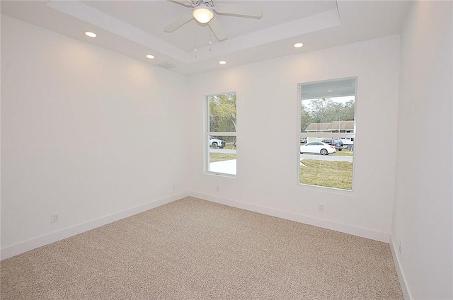 carpeted empty room featuring a raised ceiling and ceiling fan