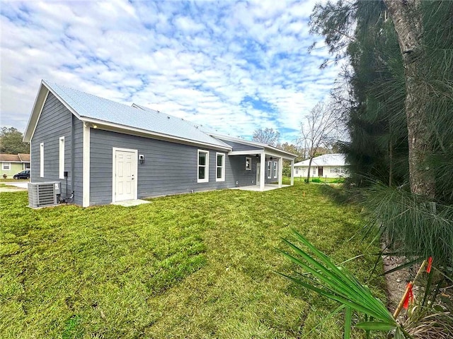 rear view of property with a lawn and central AC unit