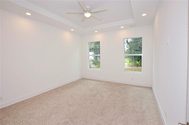 carpeted empty room featuring ceiling fan and a tray ceiling