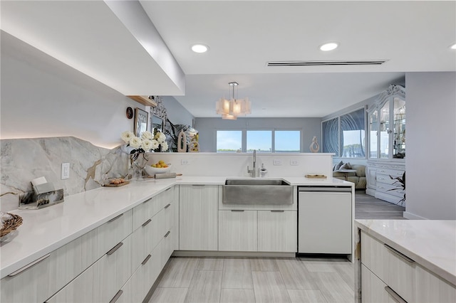 kitchen with white dishwasher, hanging light fixtures, a chandelier, sink, and backsplash