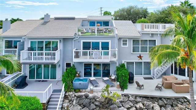 rear view of house featuring a hot tub, a patio area, and a balcony