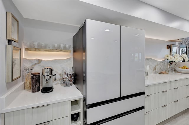 kitchen with fridge, white cabinetry, and decorative backsplash