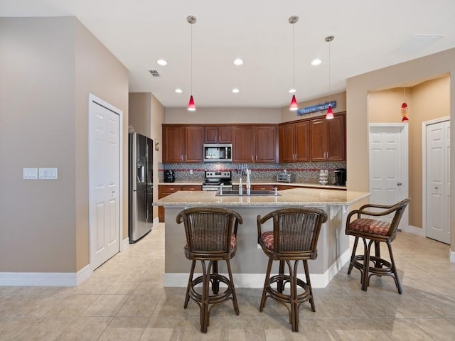 kitchen with a sink, a breakfast bar, light stone countertops, backsplash, and stainless steel appliances