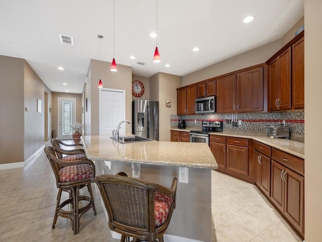 kitchen featuring tasteful backsplash, visible vents, a sink, appliances with stainless steel finishes, and a breakfast bar area